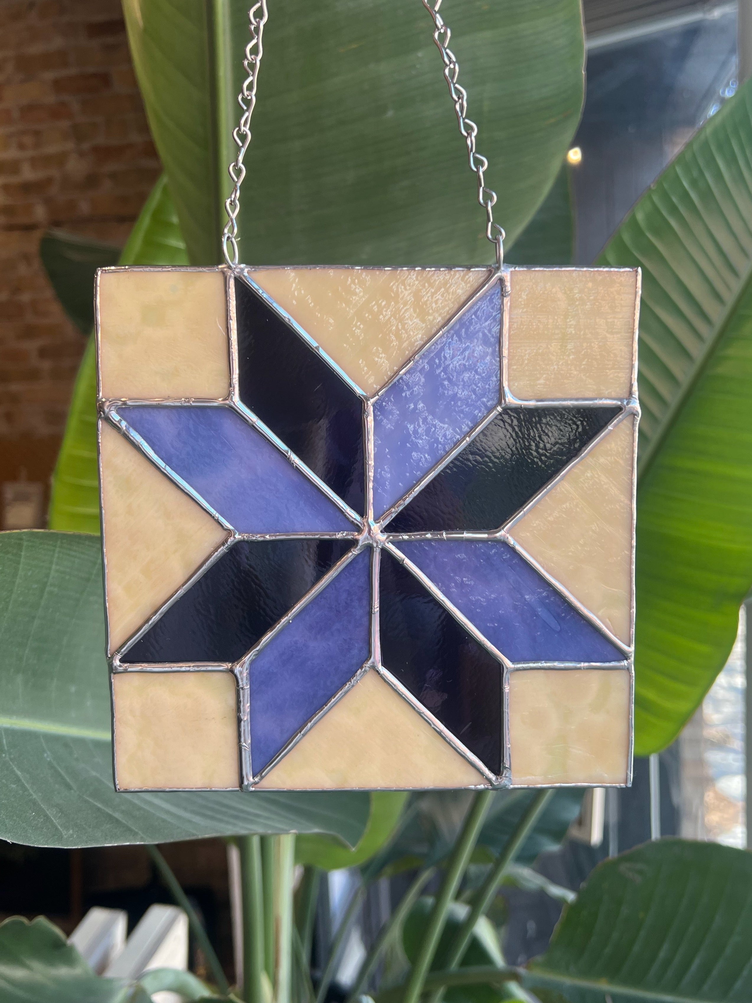 Stained glass star hanging in front of green leaves