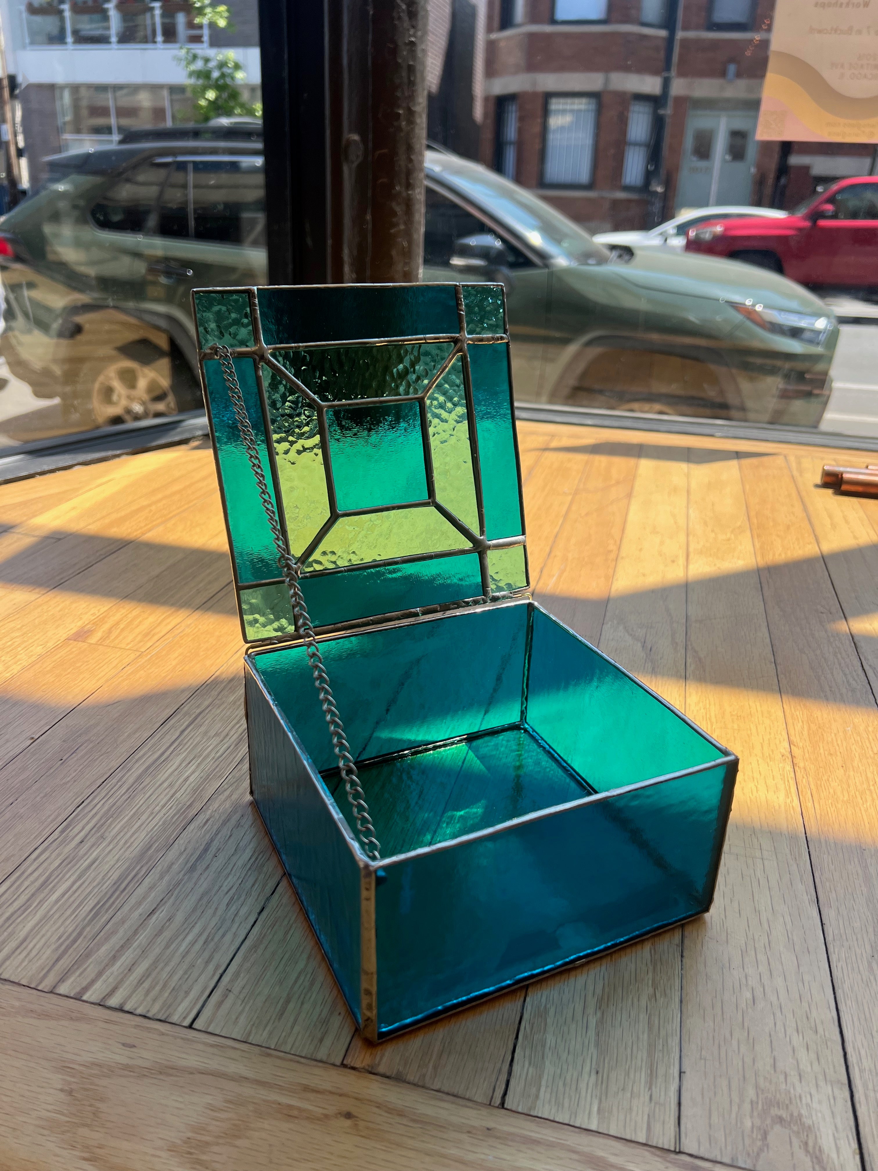Turquoise glass box with a reflective surface in an urban setting