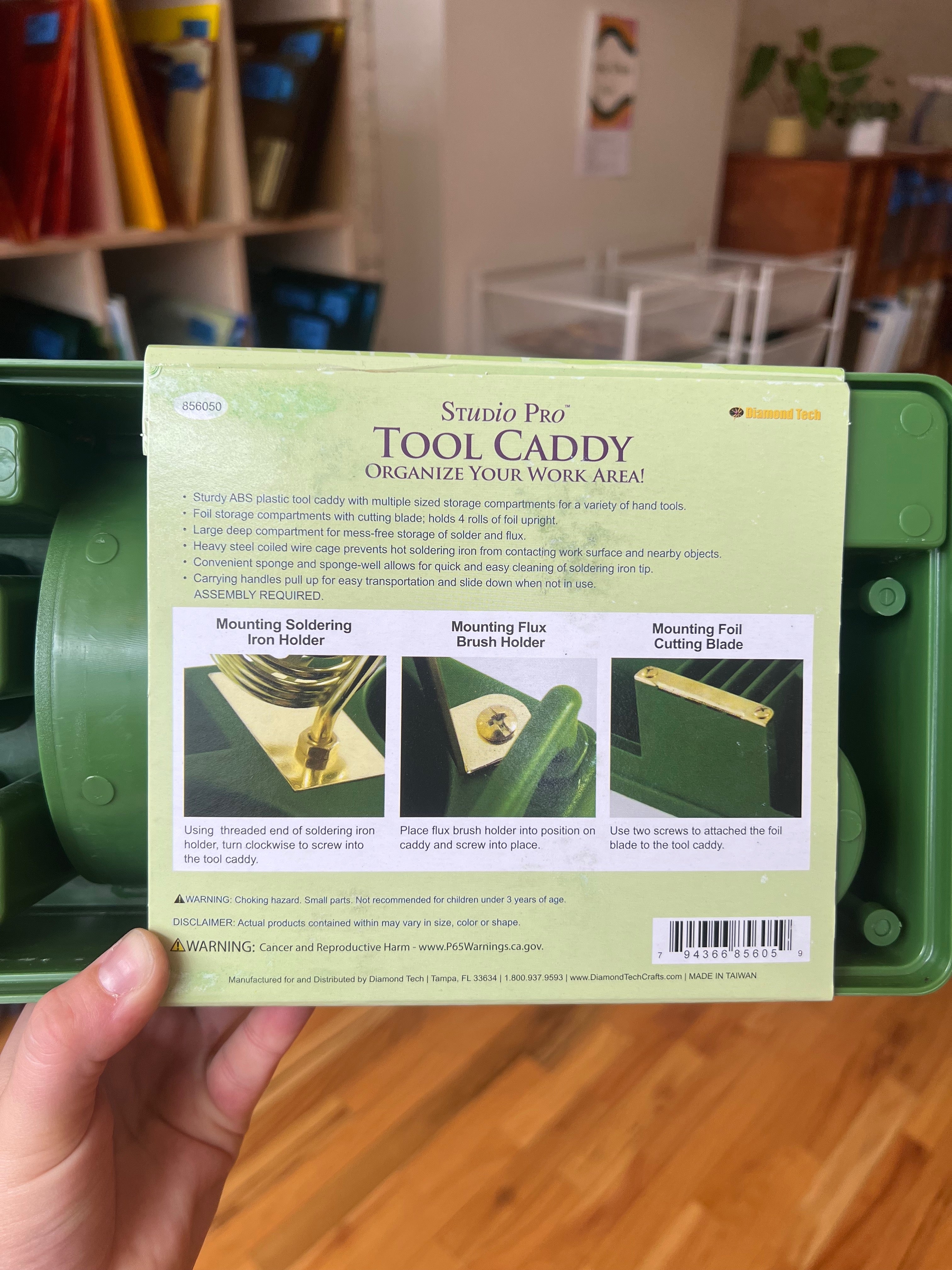 Green tool caddy with a label held by a hand, indoor setting