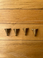 Four brass box legs on a wooden surface