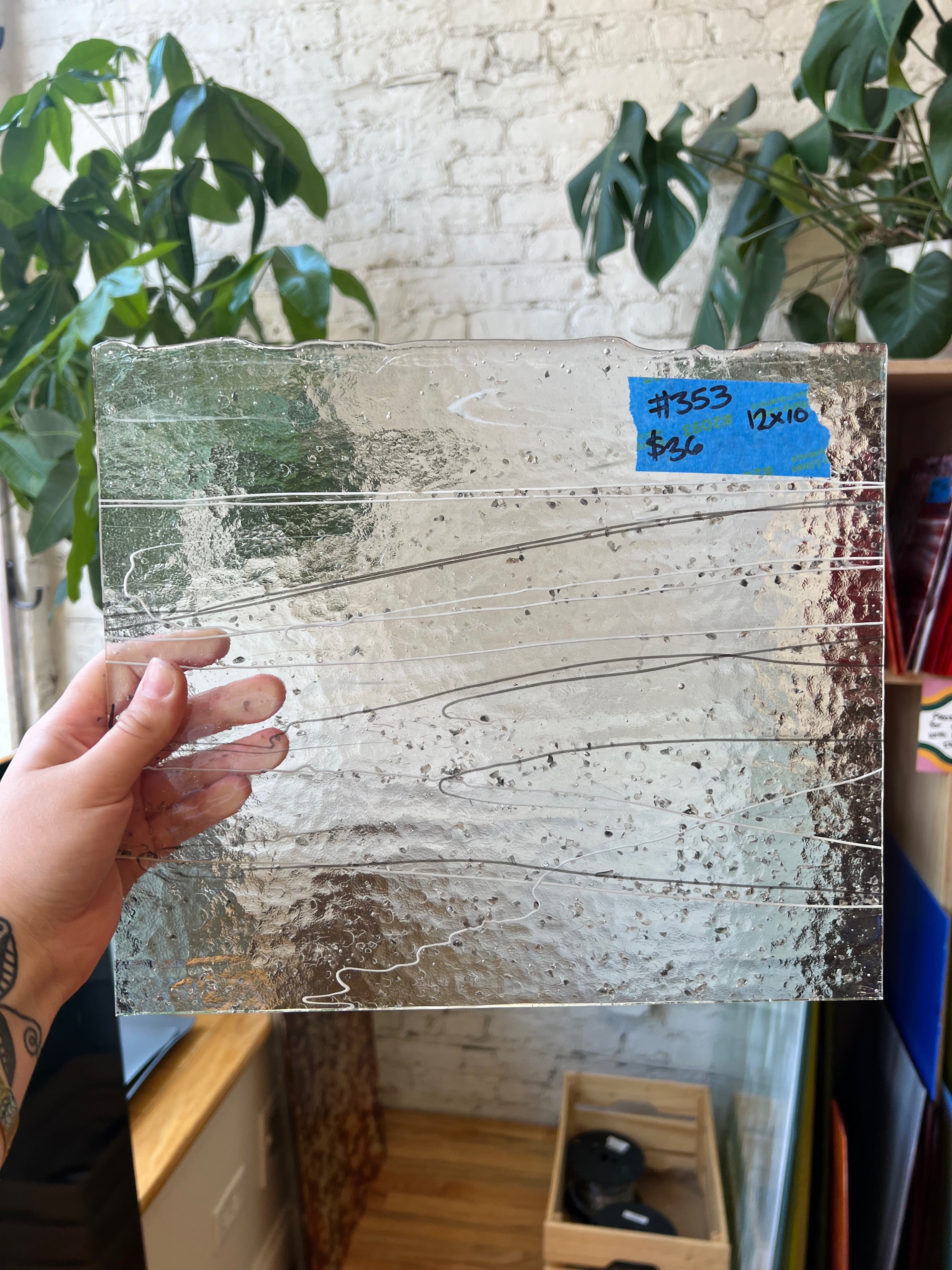 Person holding a rectangular glass pane with markings in an indoor setting