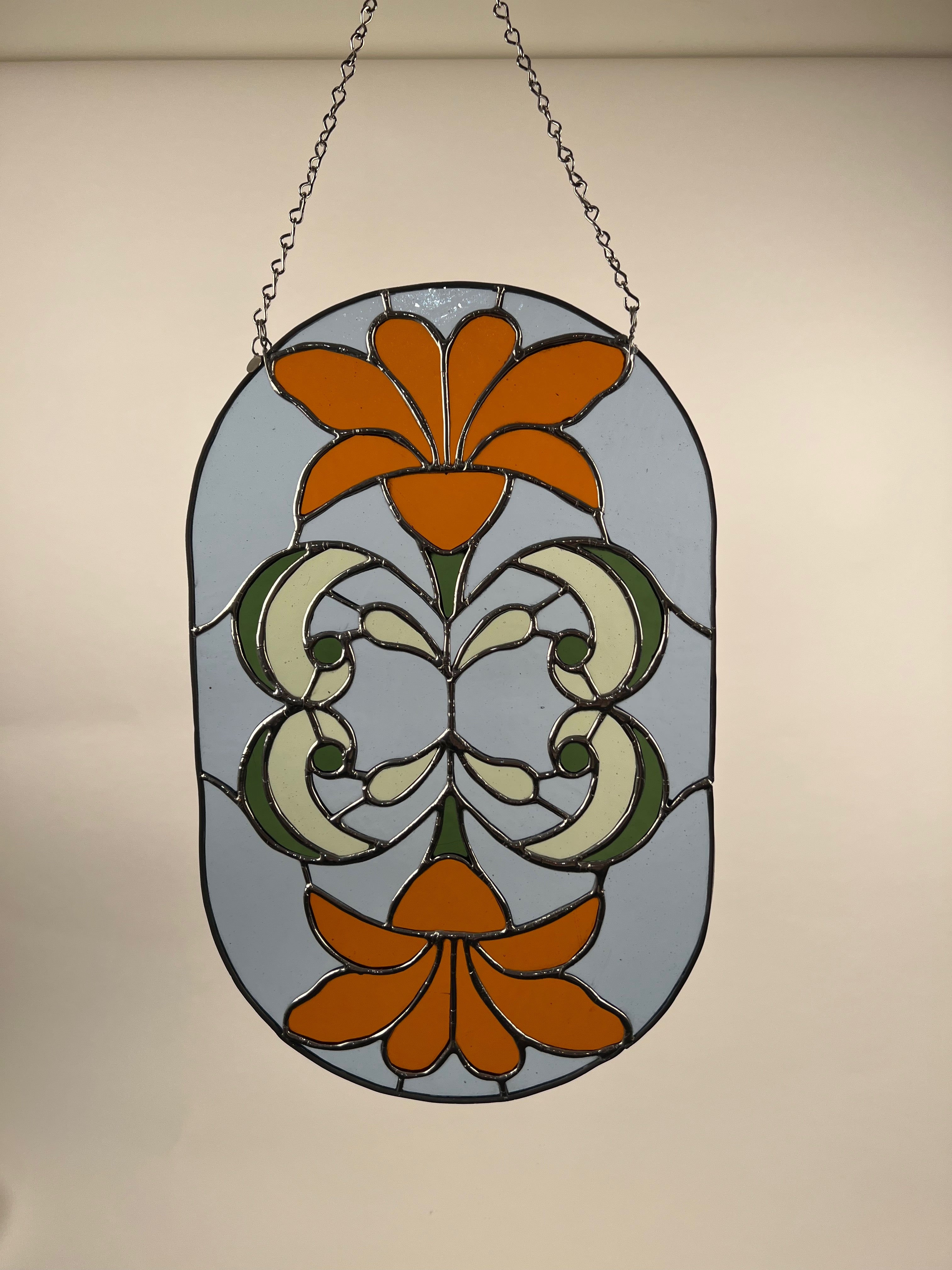 Stained glass panel with orange floral design on a beige background