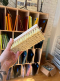 Person holding a scrub brush in front of a bookshelf with colorful books.