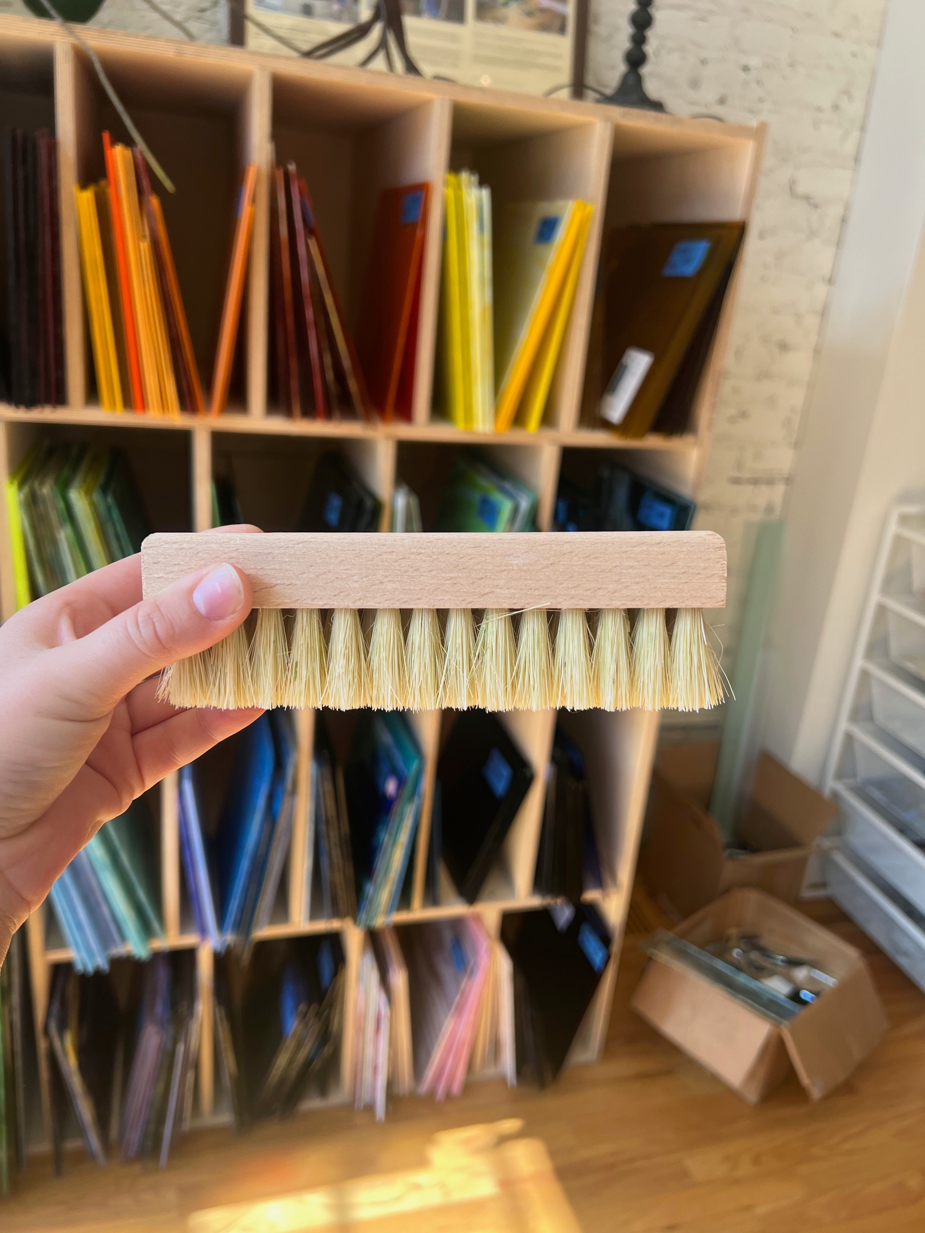 Person holding a brush in front of a bookshelf with colorful books.