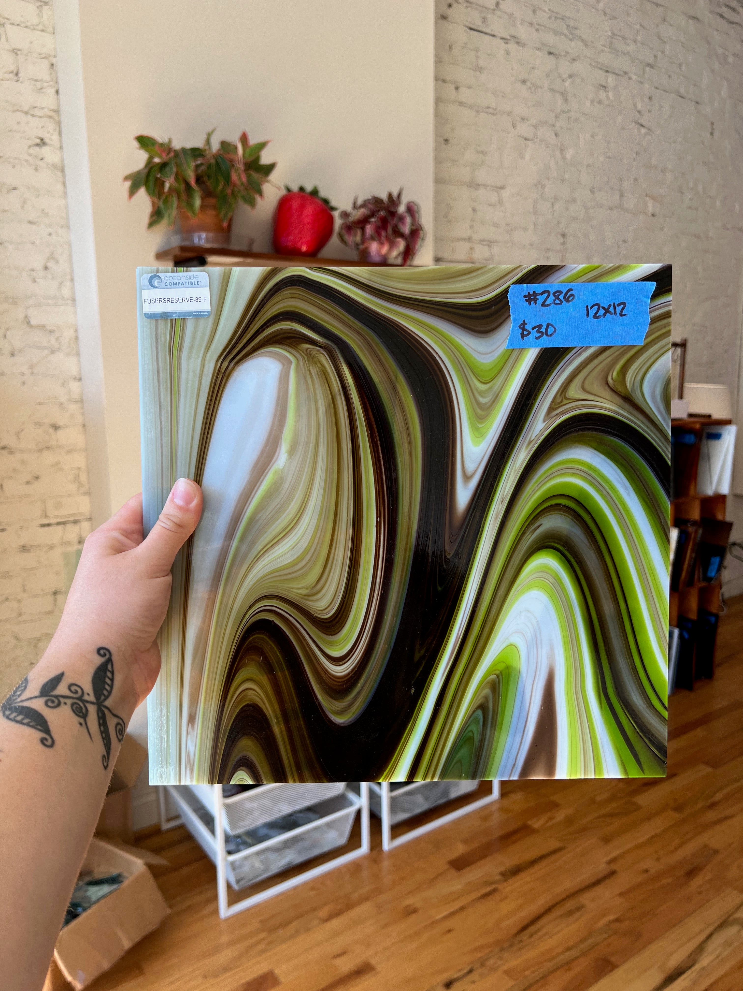 Person holding a piece of abstract glass with a brick wall and plants in the background
