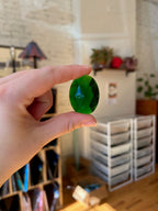 Hand holding a green stone with a blurred indoor background