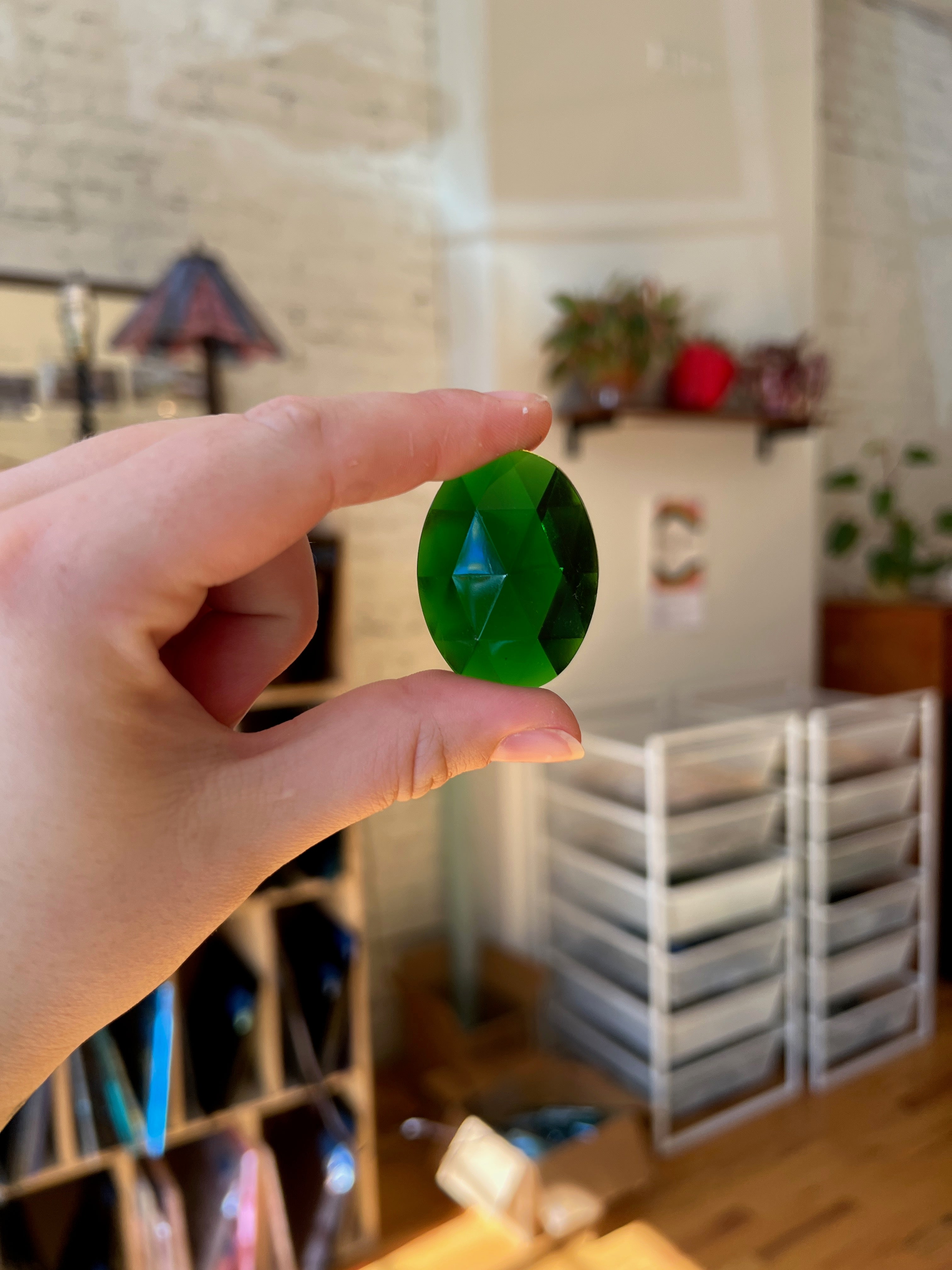 Hand holding a green stone with a blurred indoor background