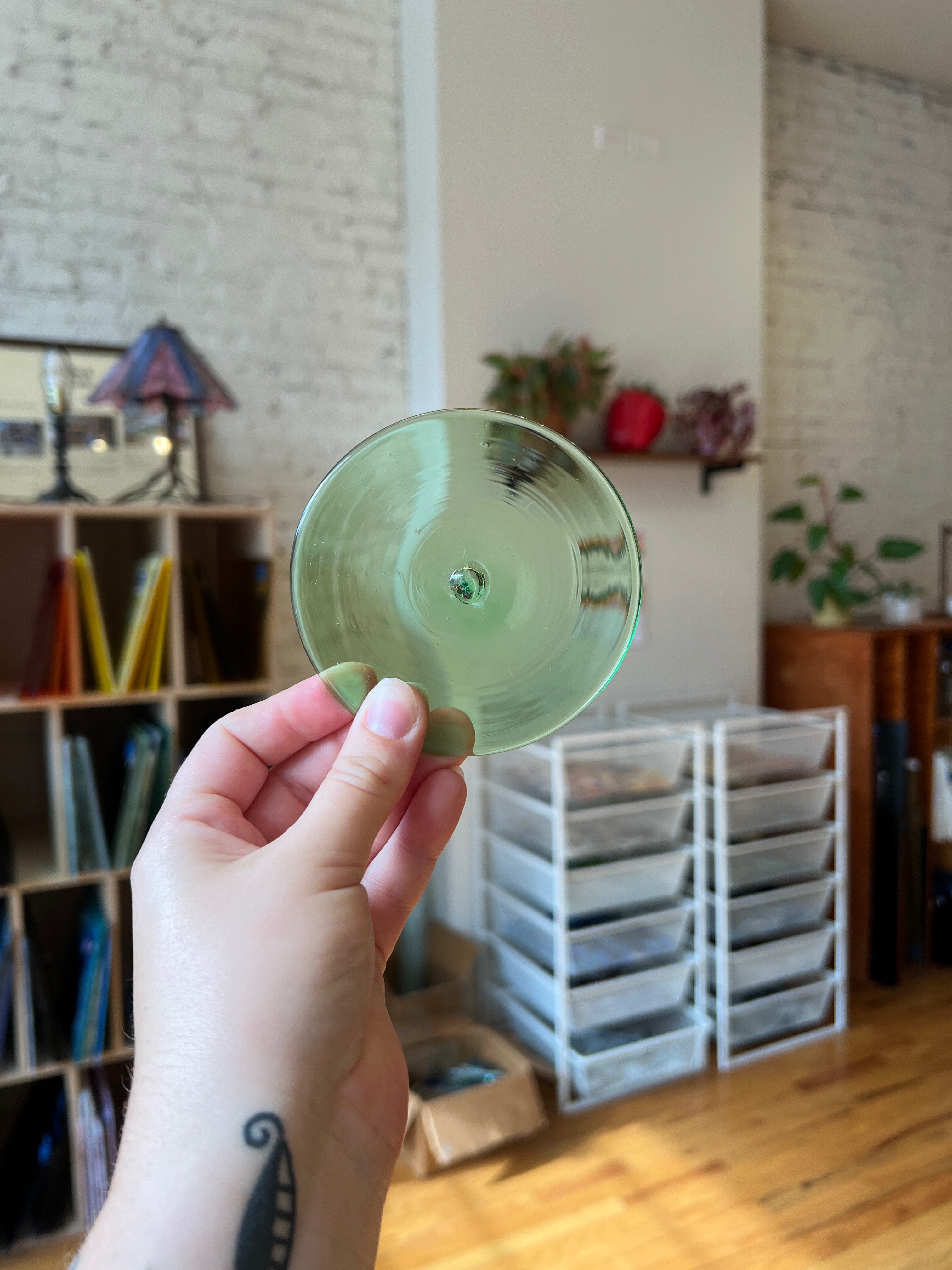 Hand holding a green rondel with a blurred indoor background