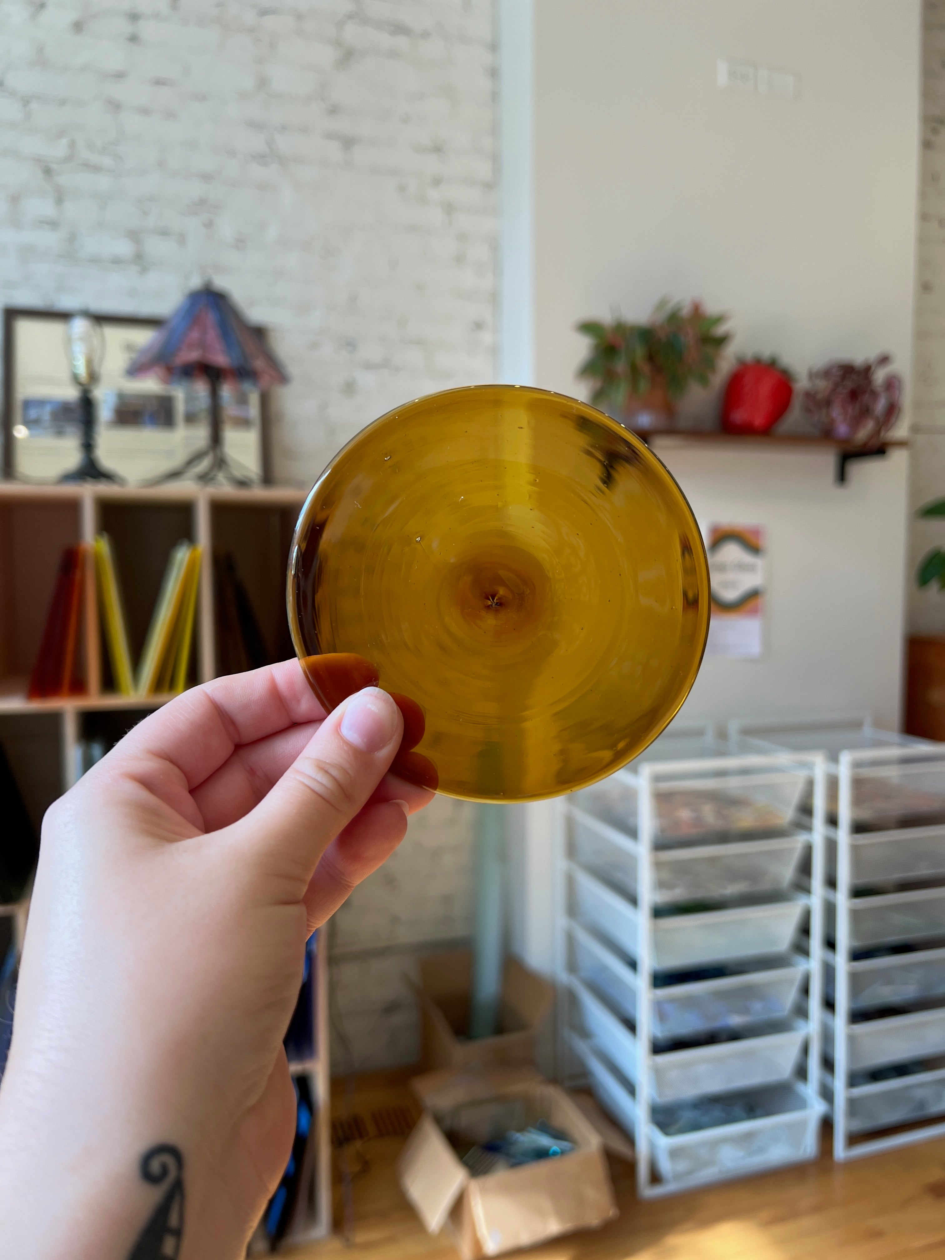 Hand holding a gold rondel with a blurred indoor background
