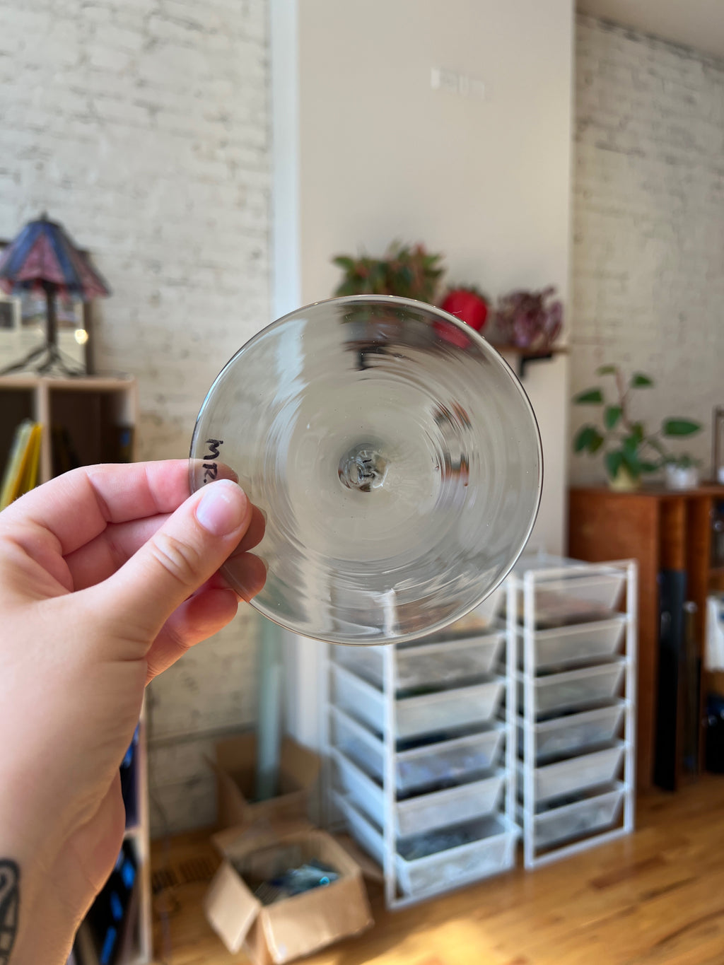 Clear glass rondel held in a hand with a room in the background