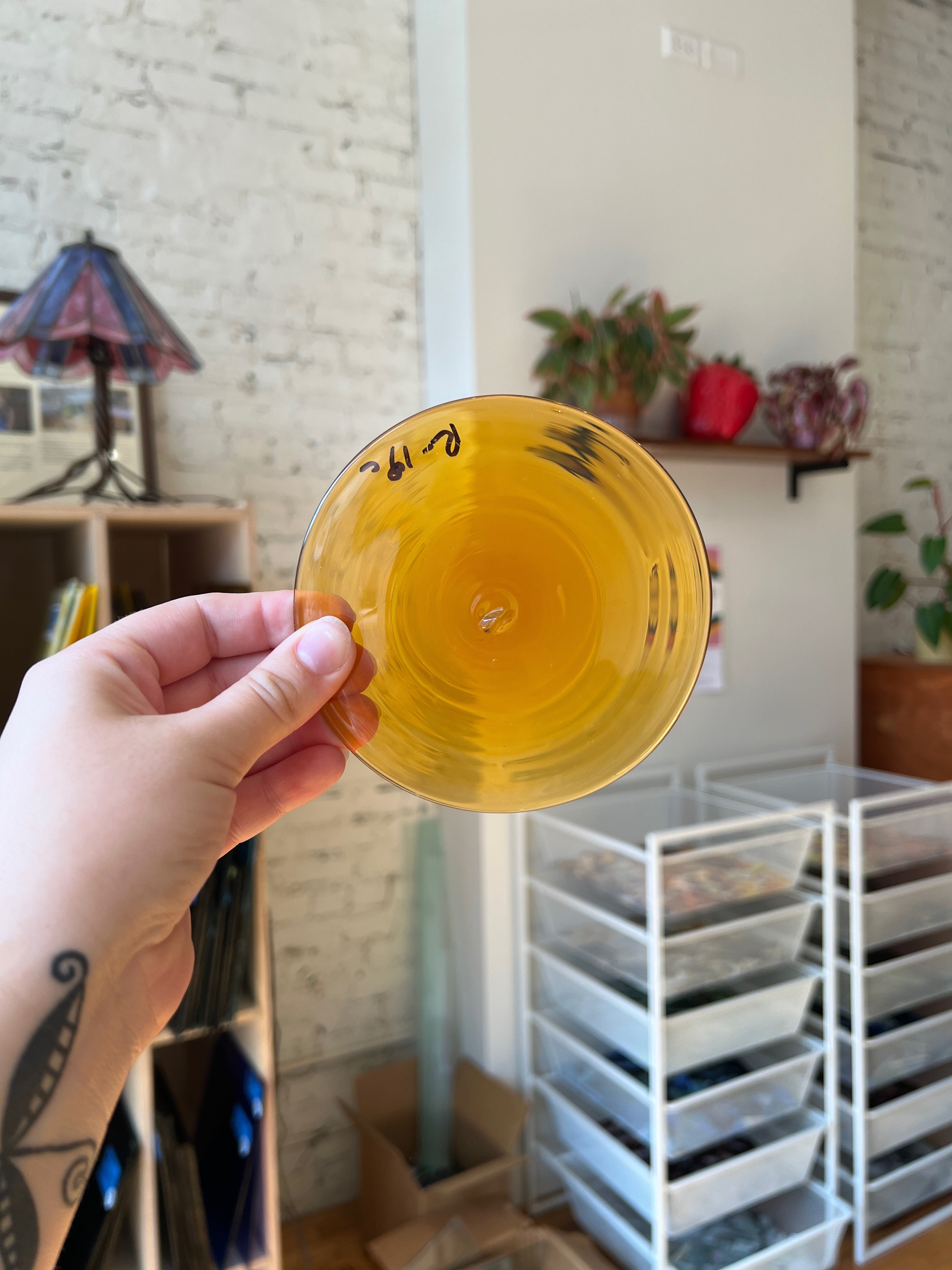 Hand holding a yellow glass rondel with a blurred indoor background