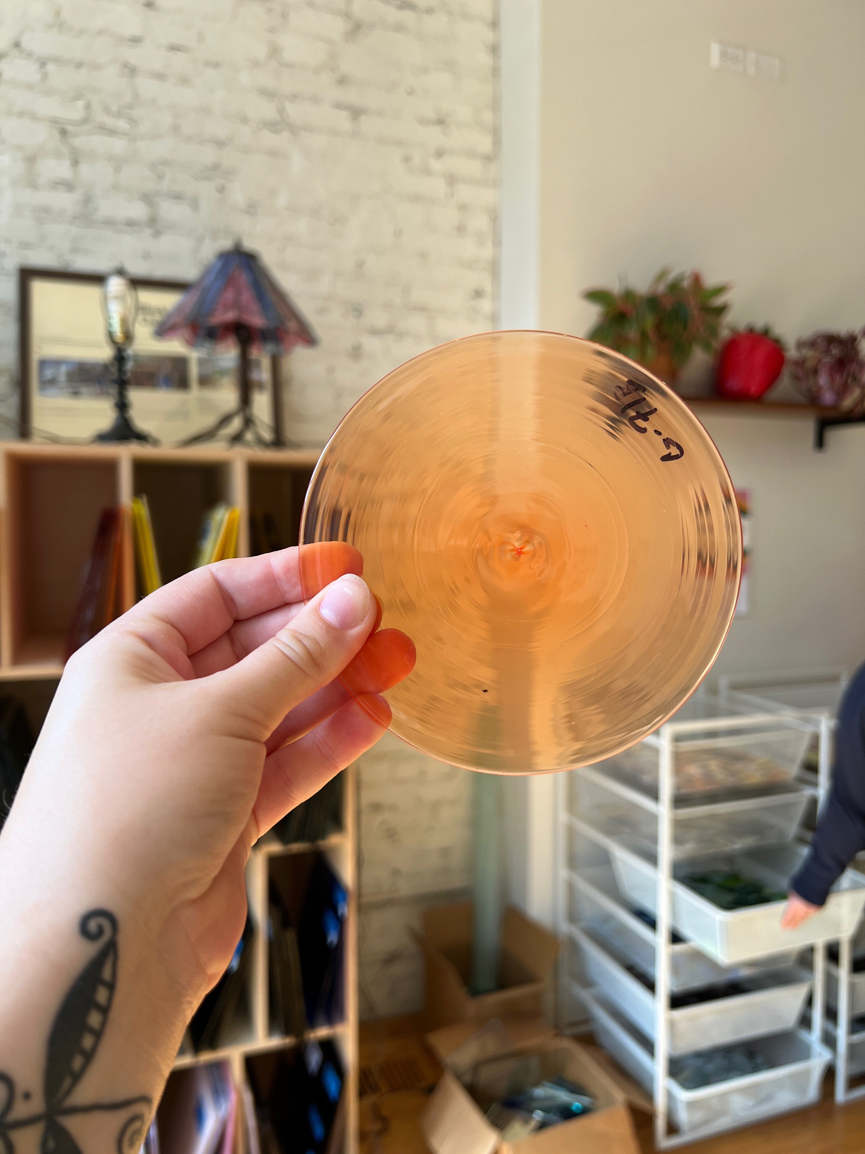 Hand holding a gold rondel with a blurred indoor background
