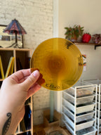 Hand holding a gold rondel with text in an indoor setting