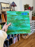 Person holding a green textured glass sheet in an indoor setting with books and stationery items.