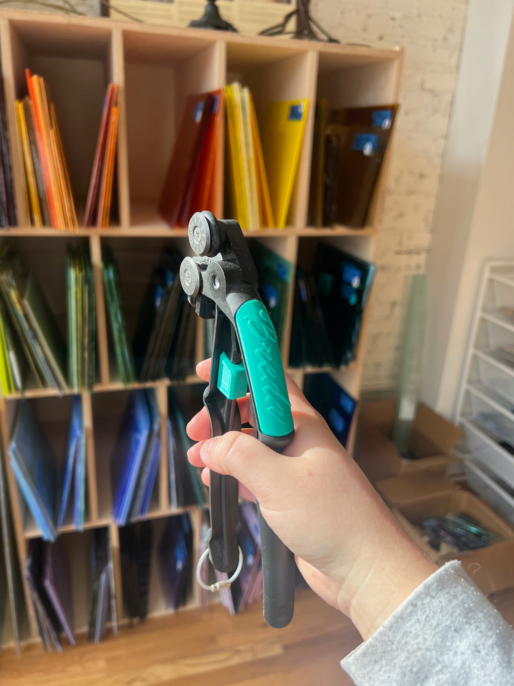 Hand holding pliers with a colorful file cabinet in the background
