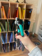 Hand holding pliers with a colorful file cabinet in the background