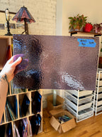 Person holding a textured lilac glass sheet in a room with shelves and decor