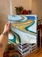 Person holding a piece of swirled colorful white stained glass with a blurred indoor background