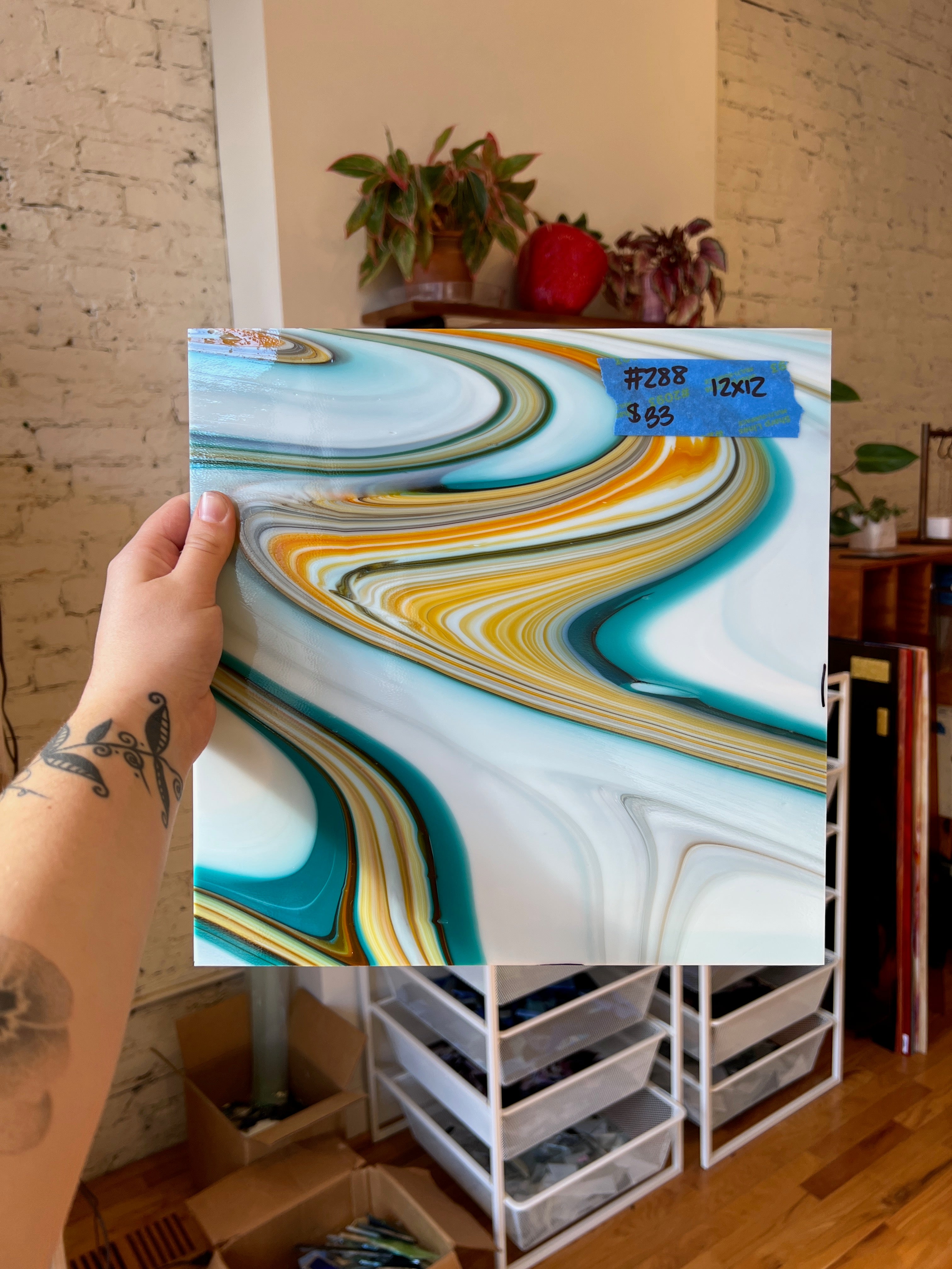 Person holding a piece of swirled colorful white stained glass with a blurred indoor background