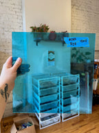 Person holding a blue transparent piece of stained glass with a room background