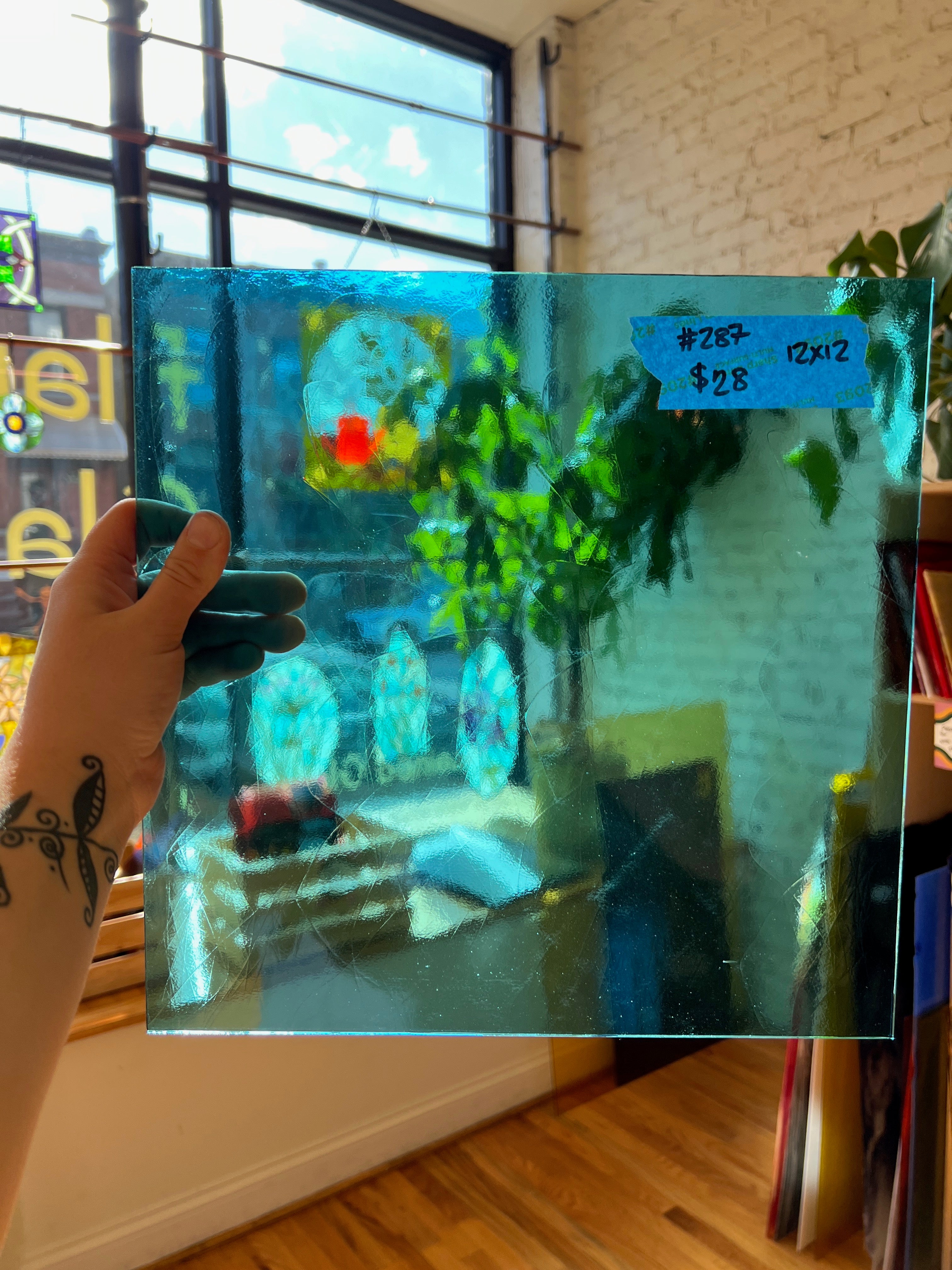Person holding a transparent piece of blue stained glass in a room with decor items.
