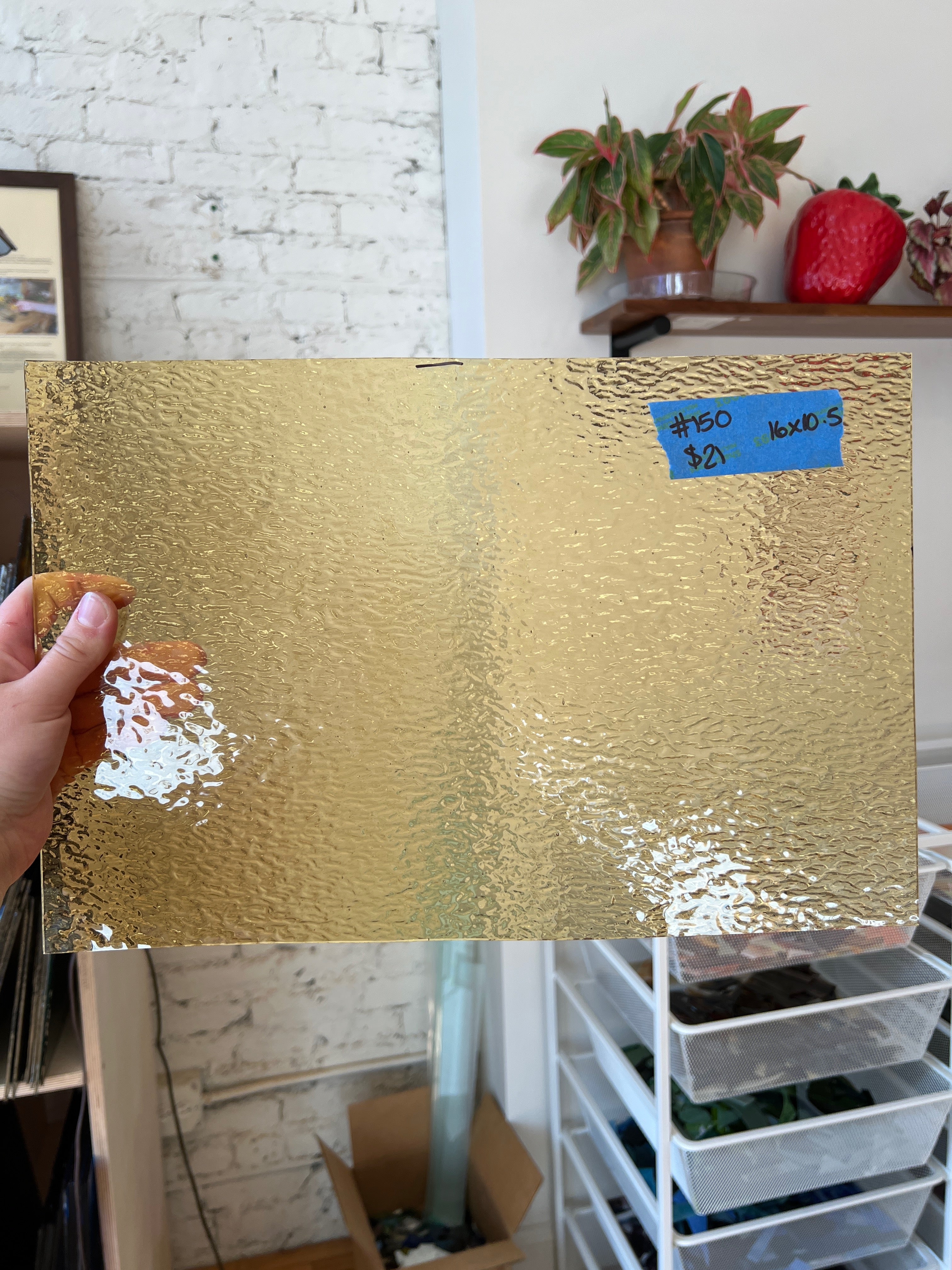 Gold textured glass sheet held up with a blurred indoor background