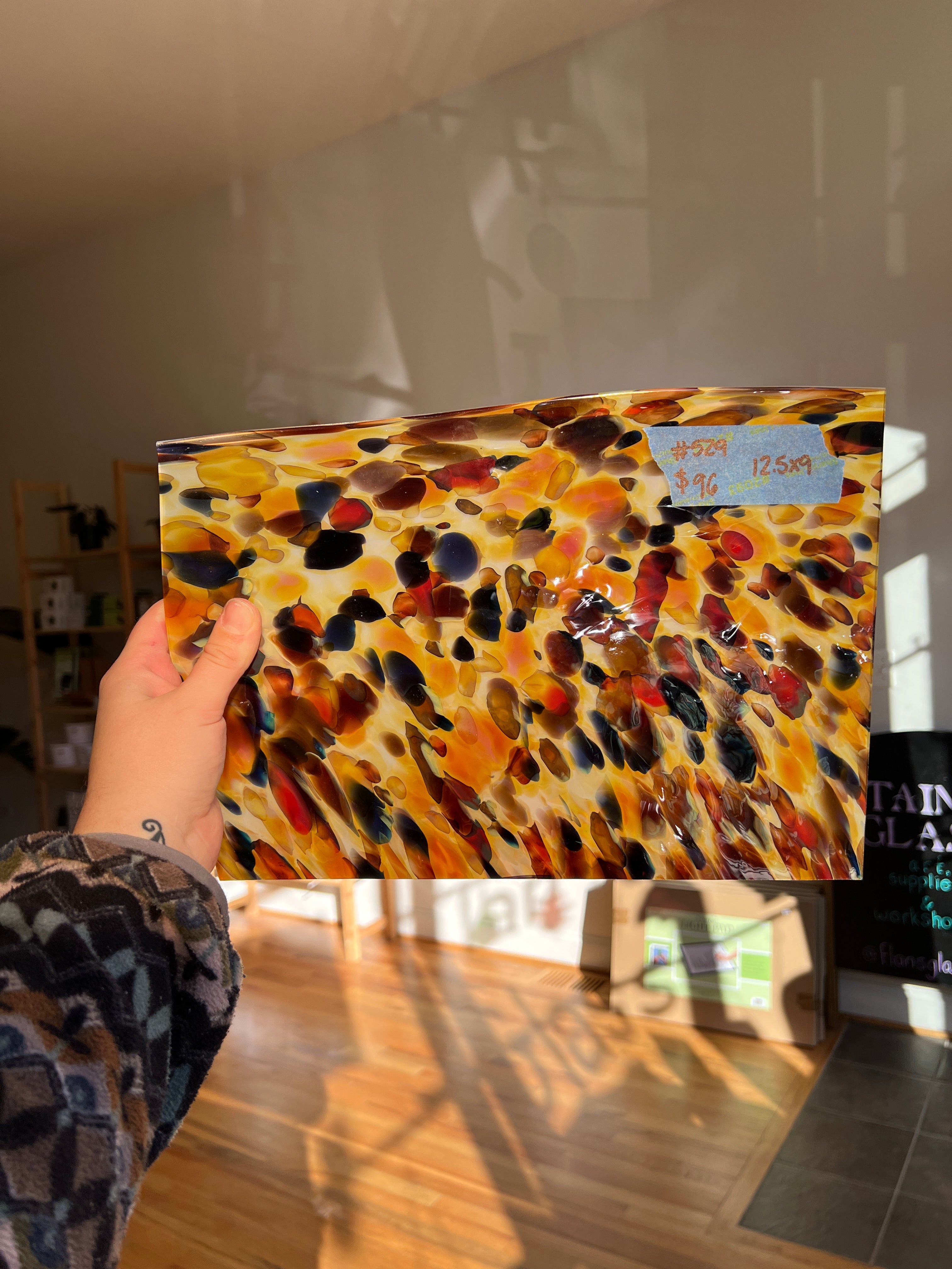 Colorful abstract glass sheet held by a person in an indoor setting