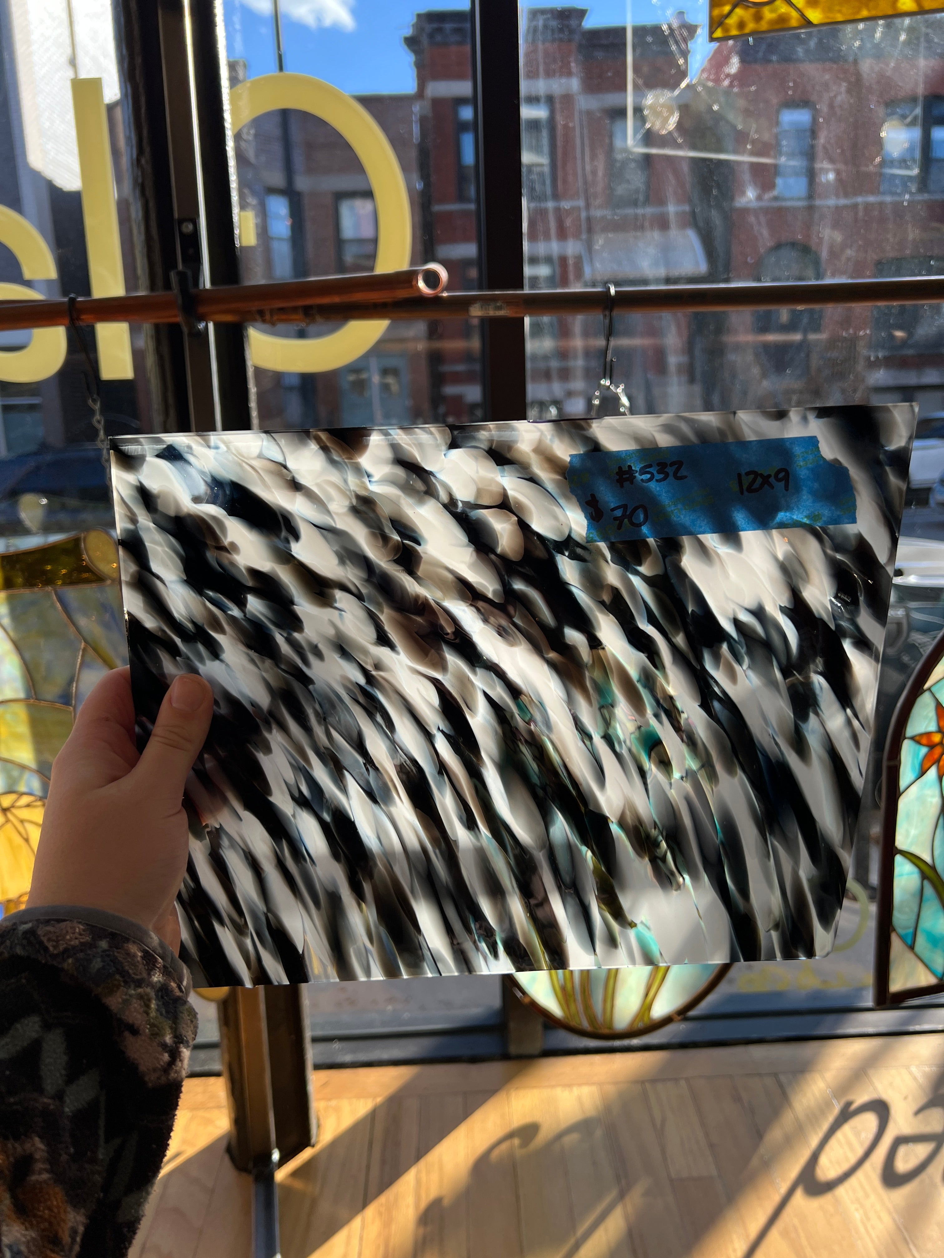 Person holding a glass sheet in front of a store window.