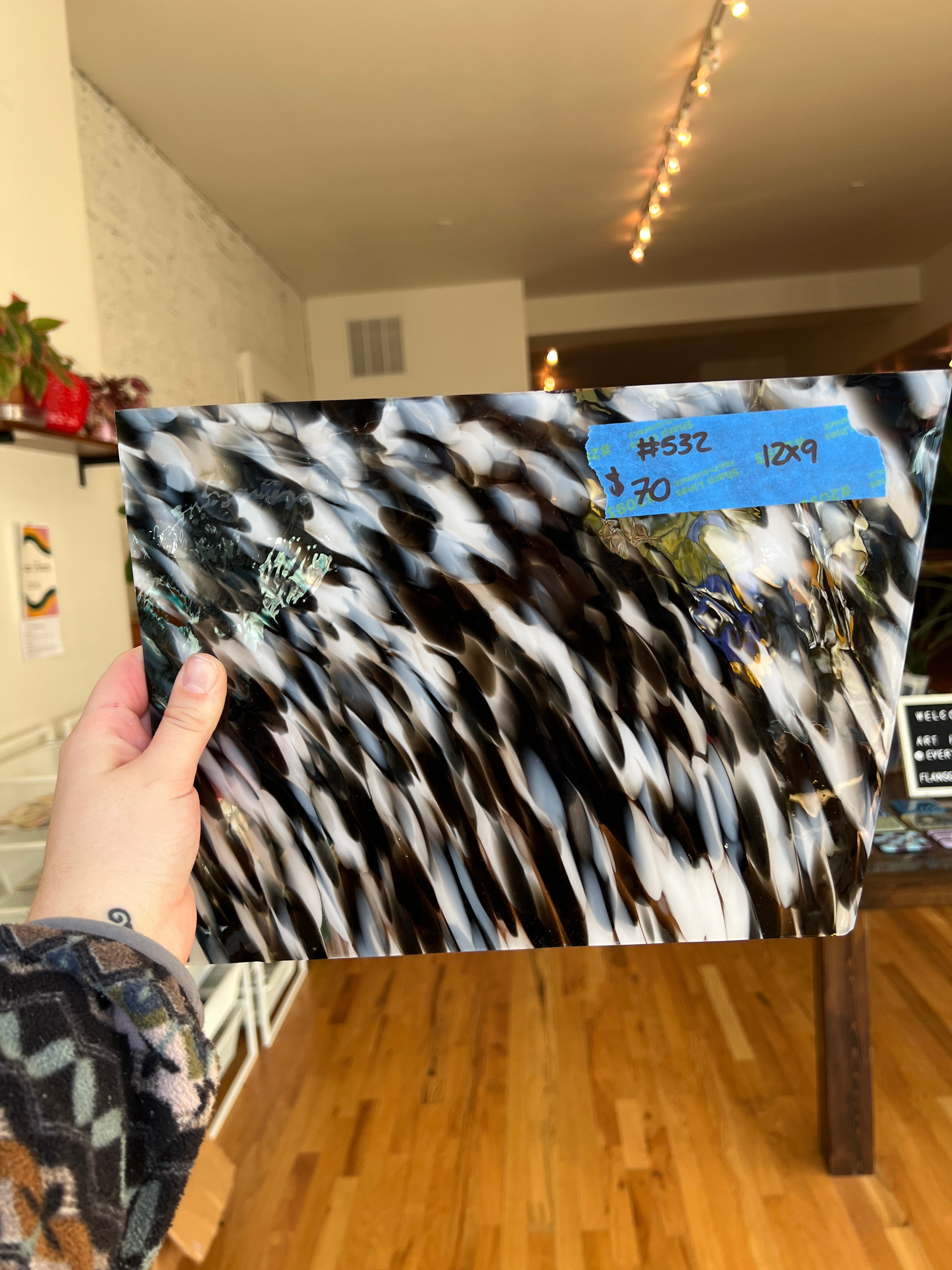 Person holding a patterned glass sheet with a blurred indoor background
