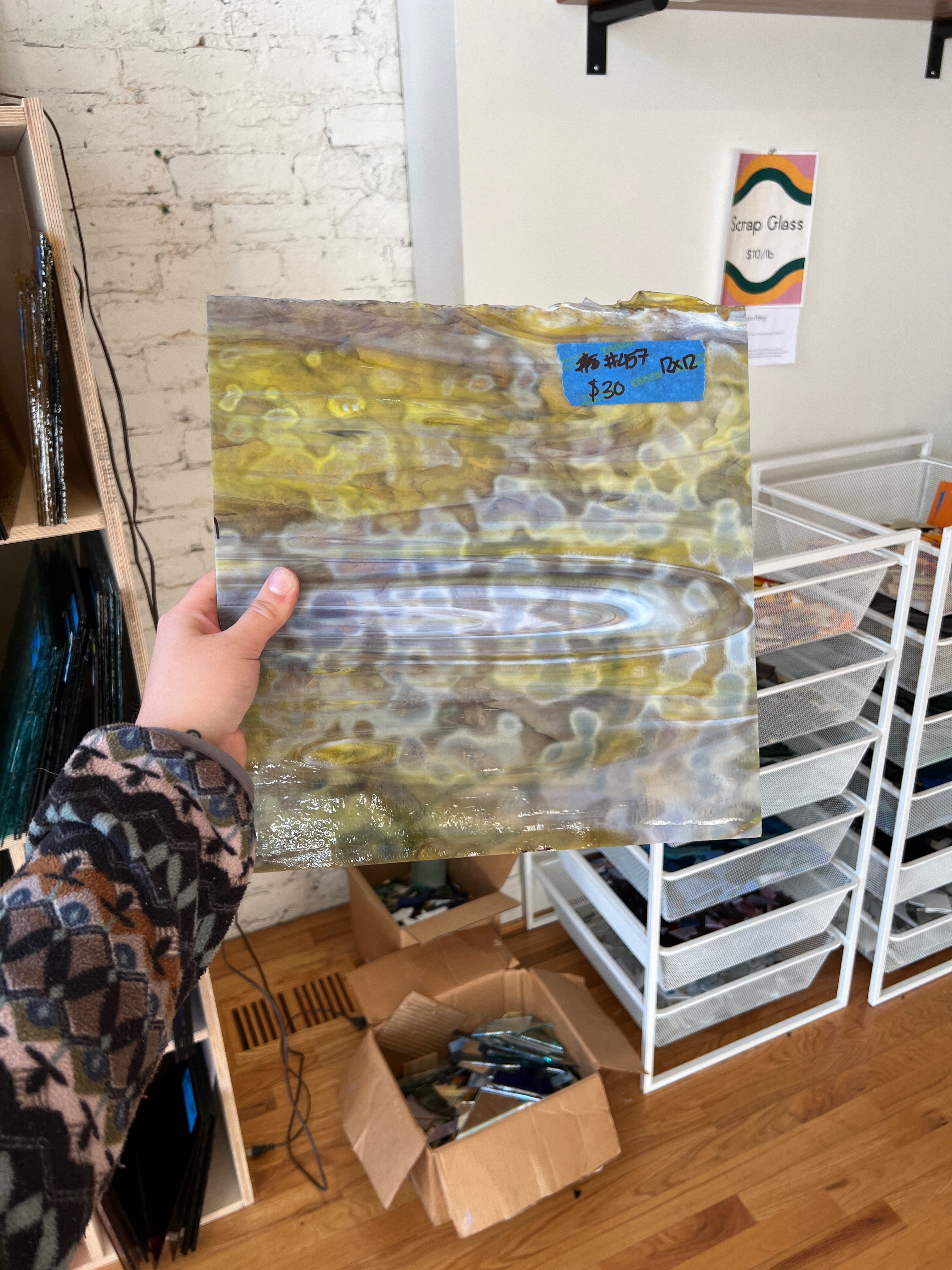 Person holding a sheet of glass, in a store setting.