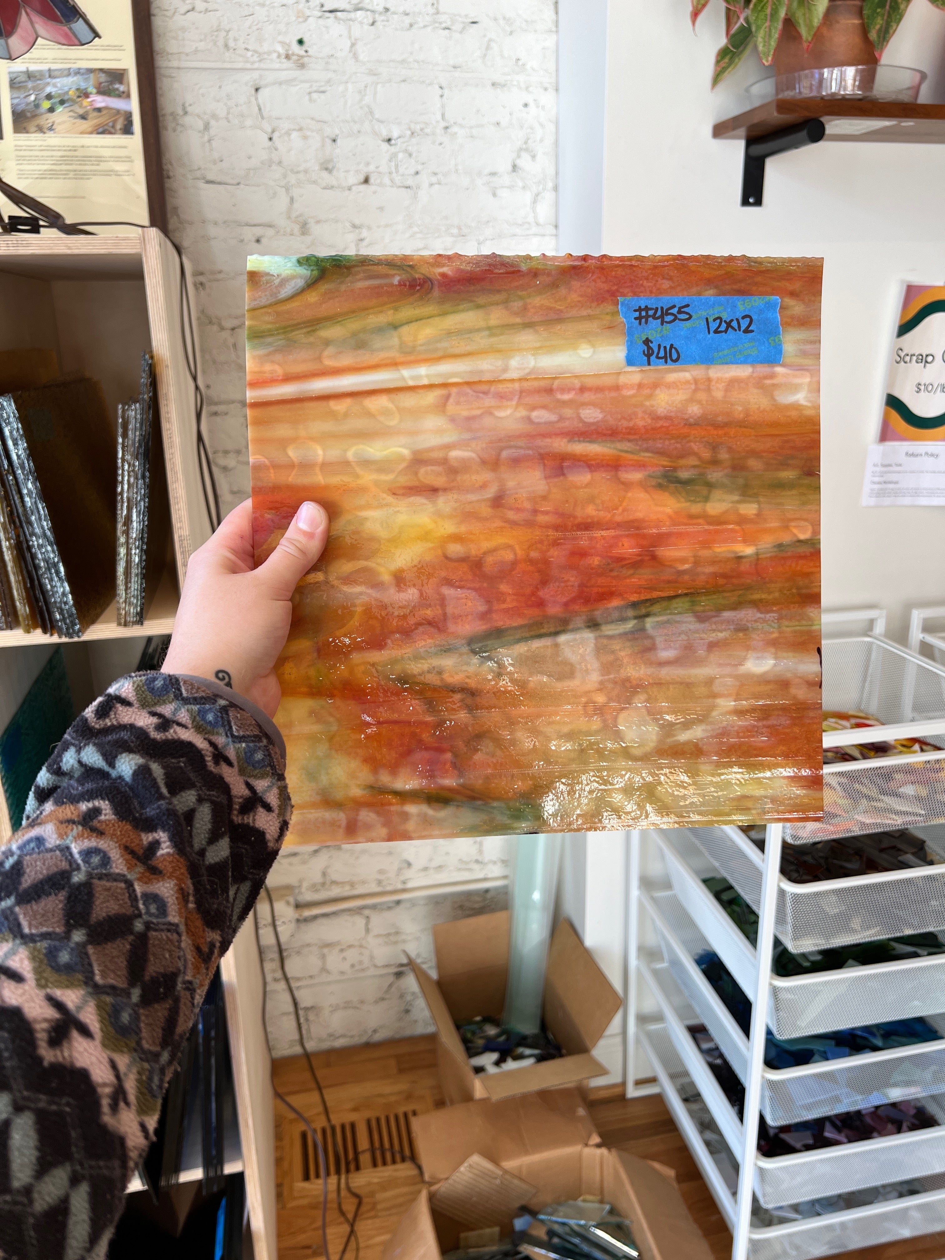 Person holding a colorful glass sheet in an art studio setting