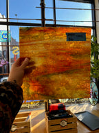 Hand holding a glass sheet with a cityscape background