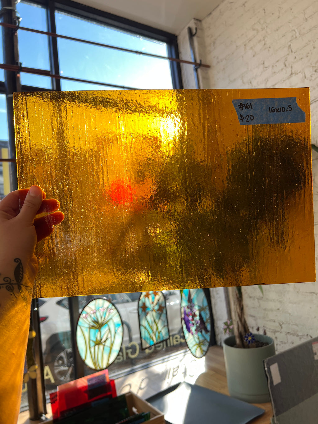 Gold glass sheet held by a hand with a blurred background