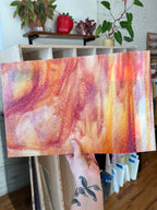 Person holding a piece of abstract glass with swirling colors in a casual setting.