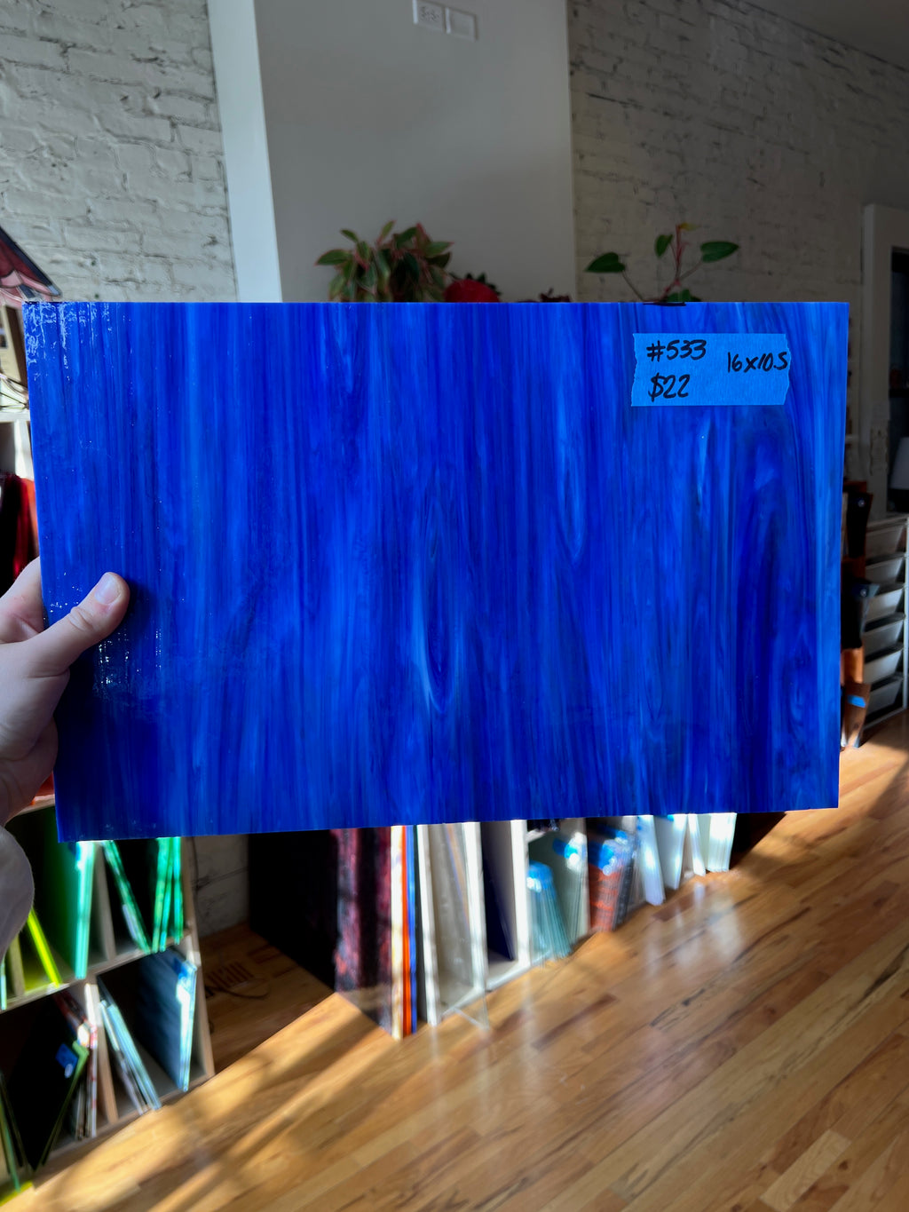 Blue glass sheet held by a hand with a blurred indoor background