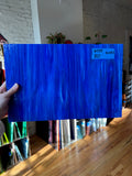 Blue glass sheet held by a hand with a blurred indoor background