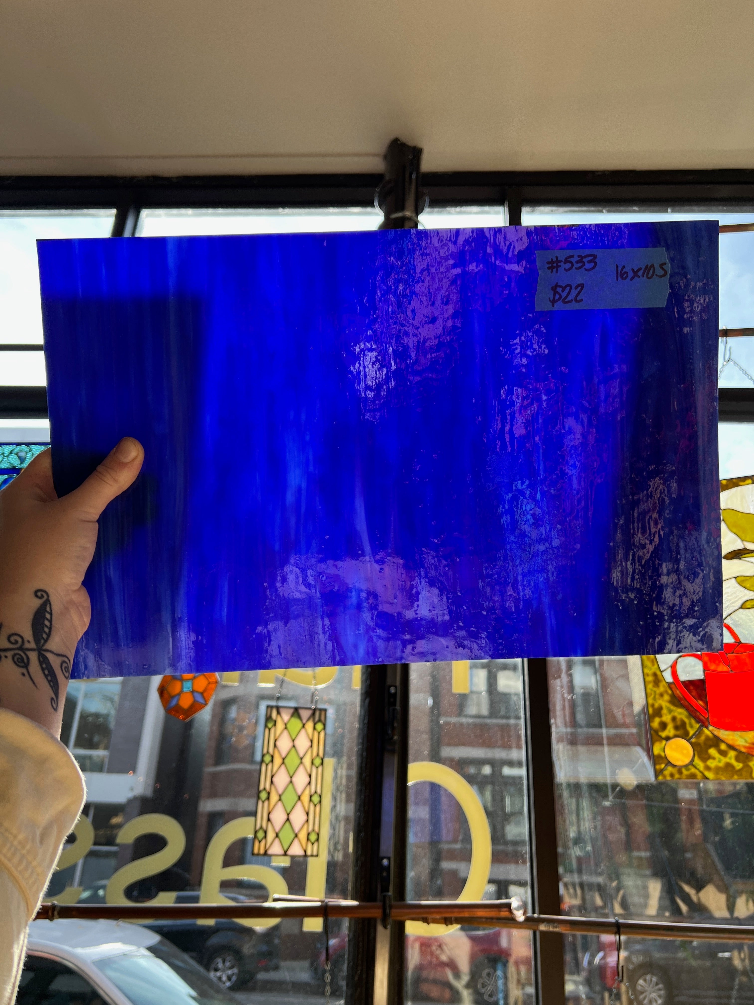 Person holding a blue glass sheet in front of a store window