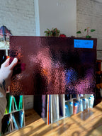Person holding a piece of glass with a blurred indoor background