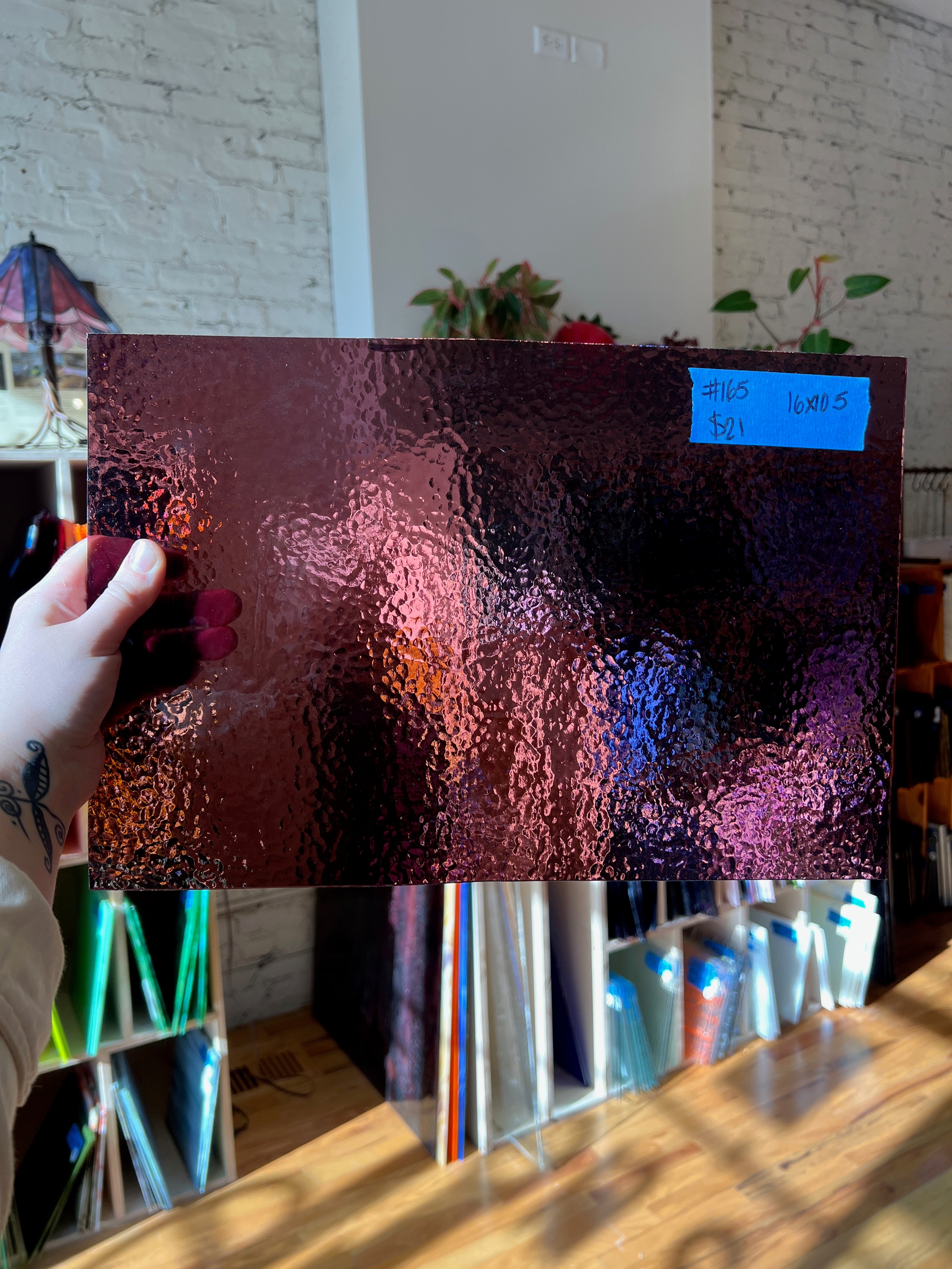 Person holding a piece of glass with a blurred indoor background