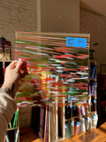 Colorful abstract glass sheet held by a person with a brick wall background