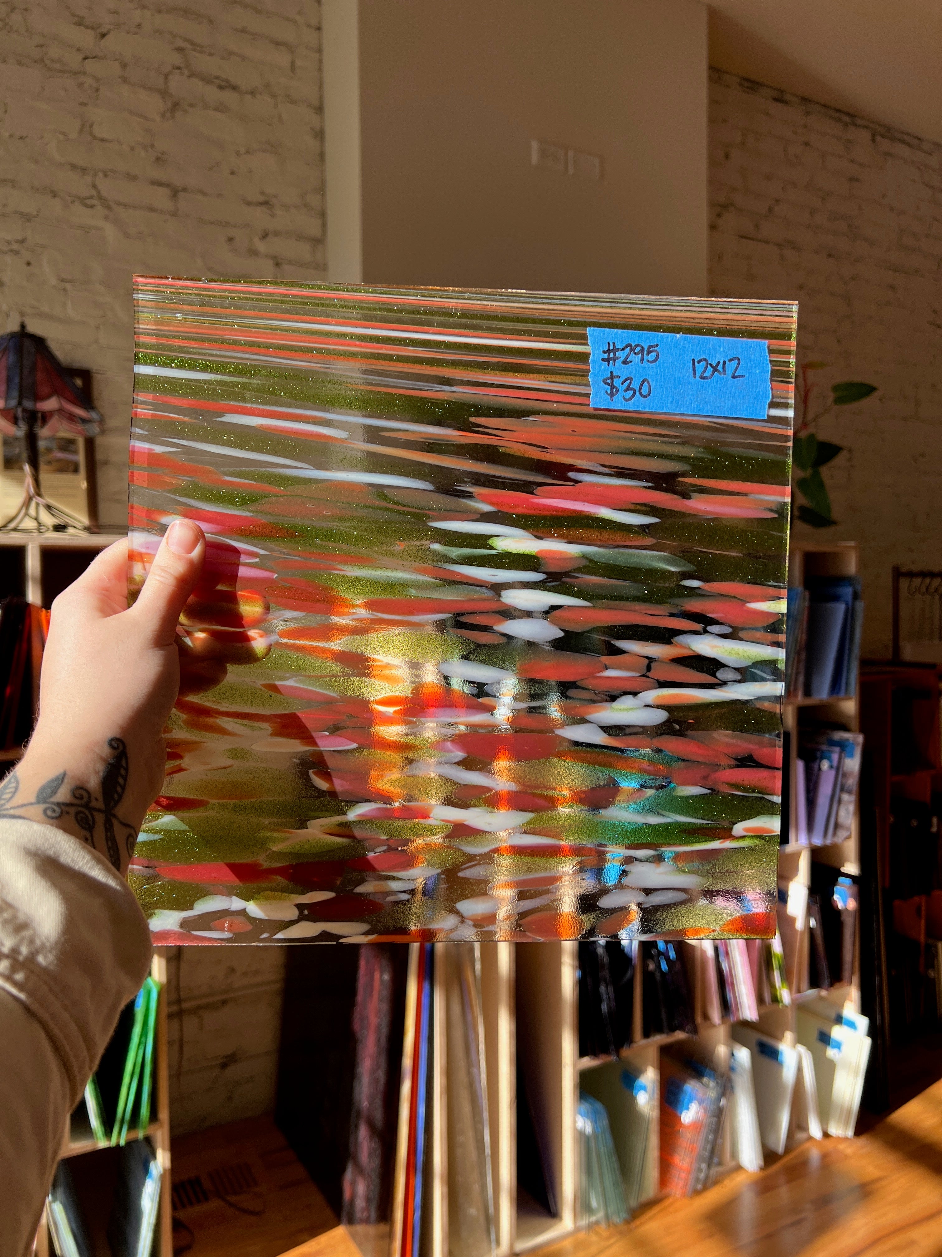 Colorful abstract glass sheet held by a person with a brick wall background