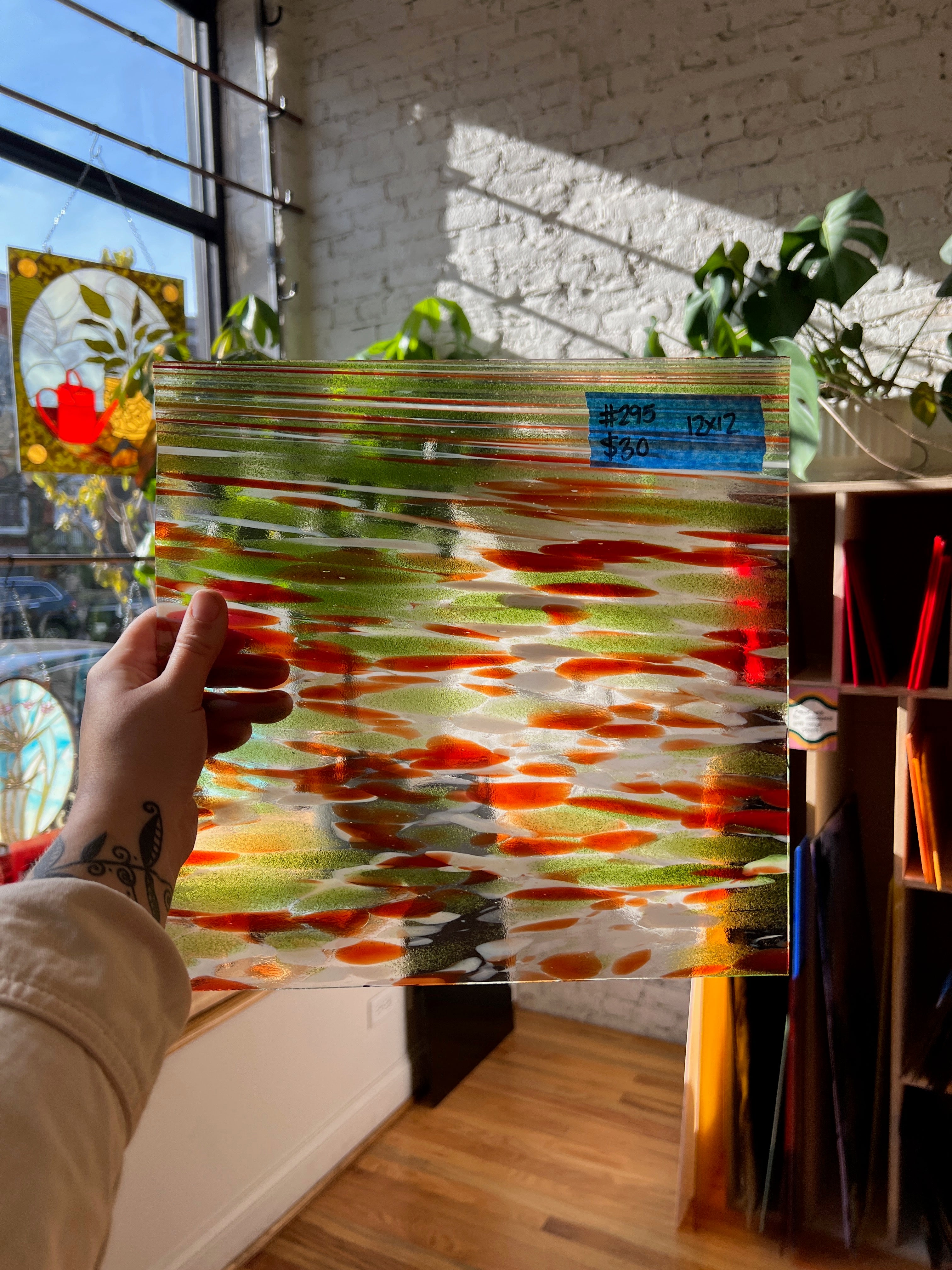 Person holding a piece of colorful glass with a blurred indoor background