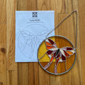 Stained glass luna moth on a wooden surface with a pattern sheet underneath