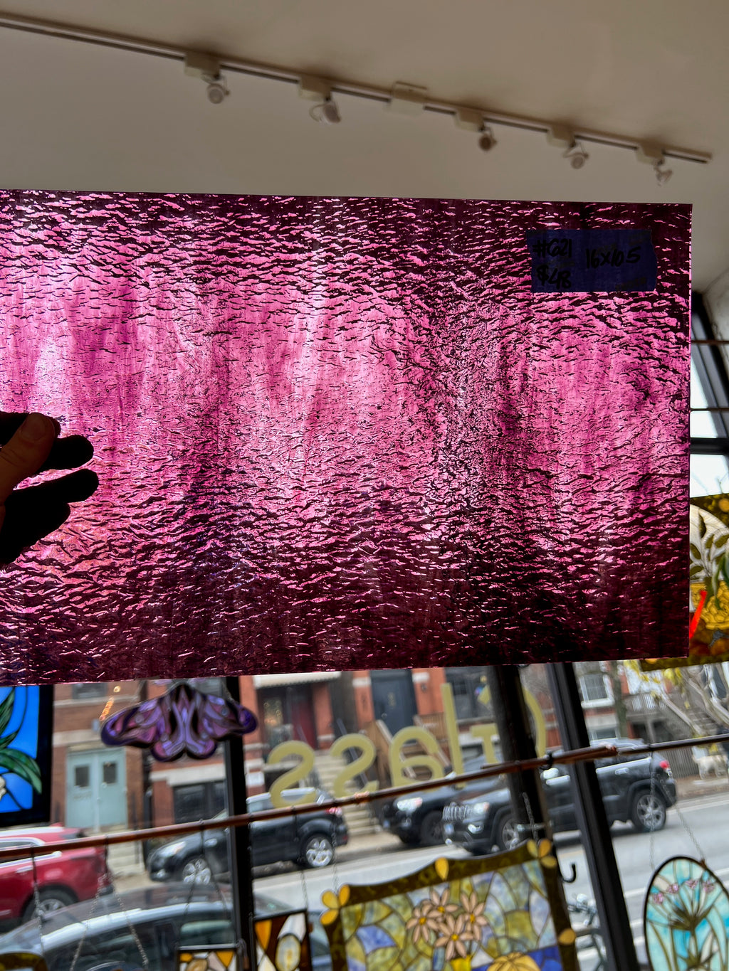 Large pink textured glass on a wall with a window view of a street scene.