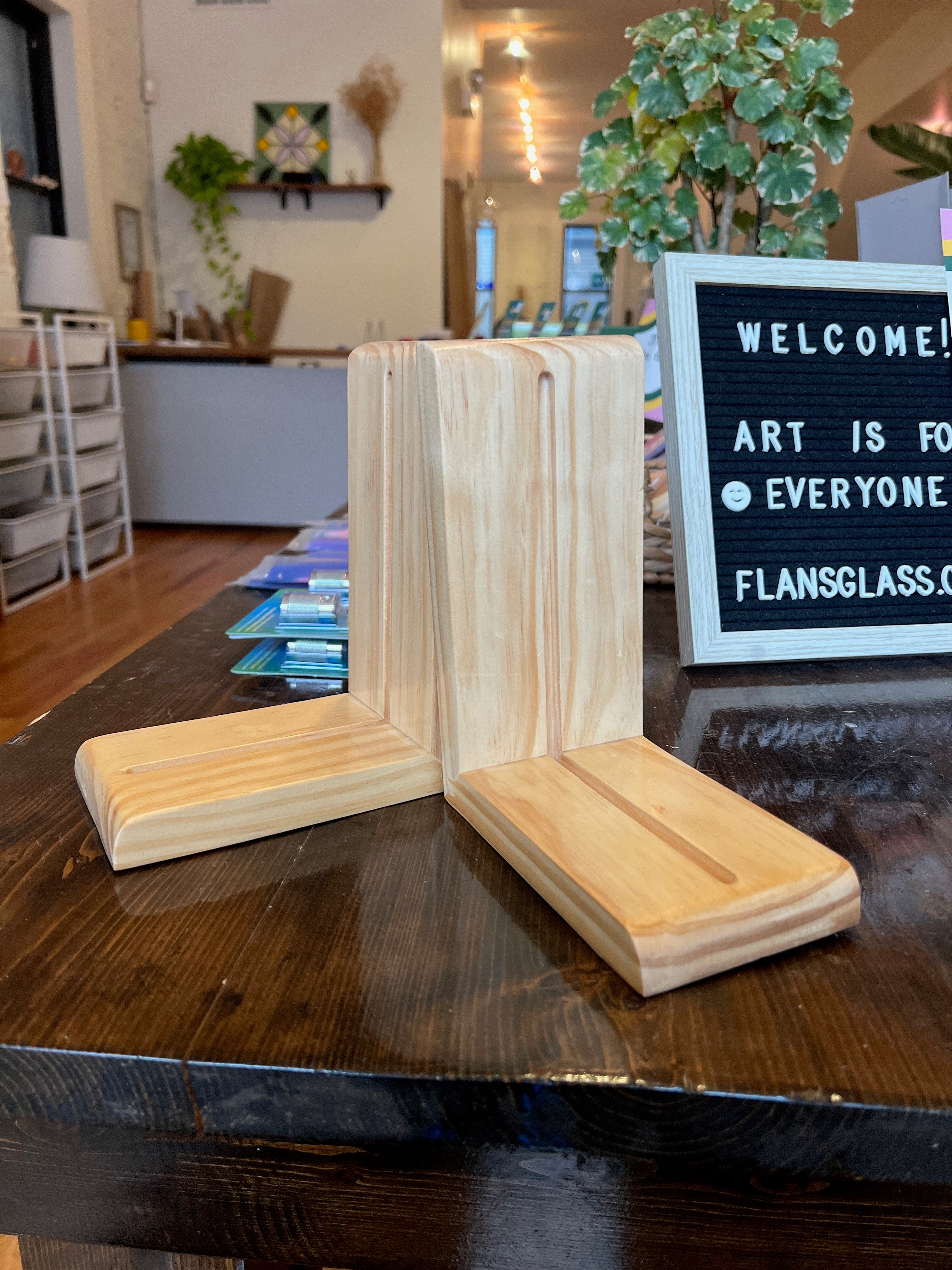 Wooden bookends on a table with a 'Welcome' sign in the background