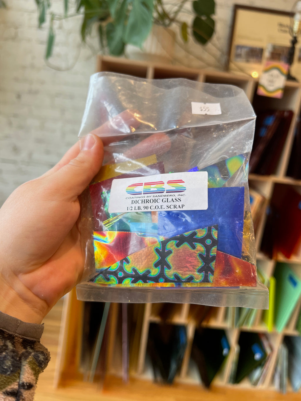 Hand holding a package of Dichroic Glass with a colorful label.