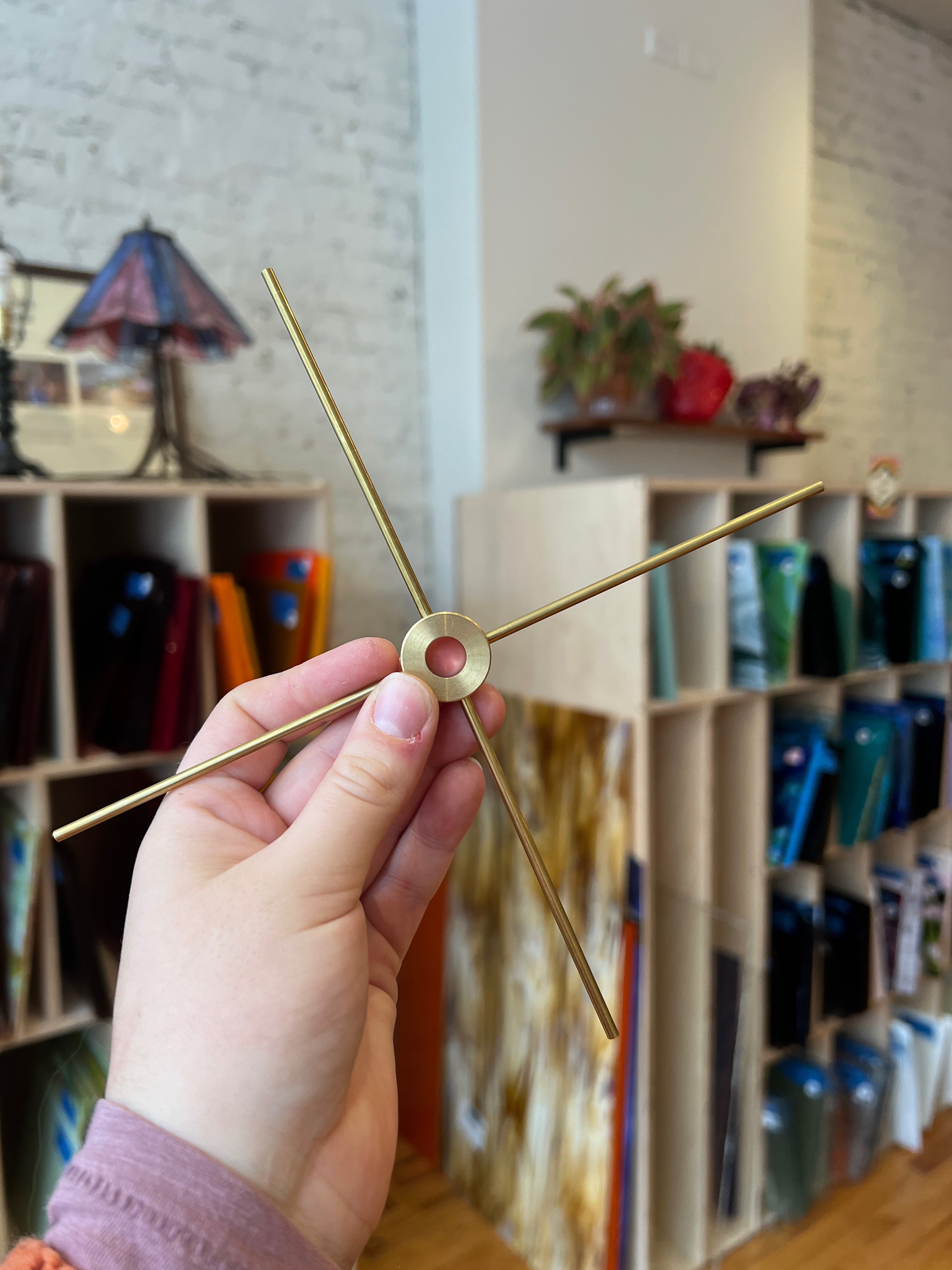 Hand holding a brass-colored object for lamp against a blurred indoor background