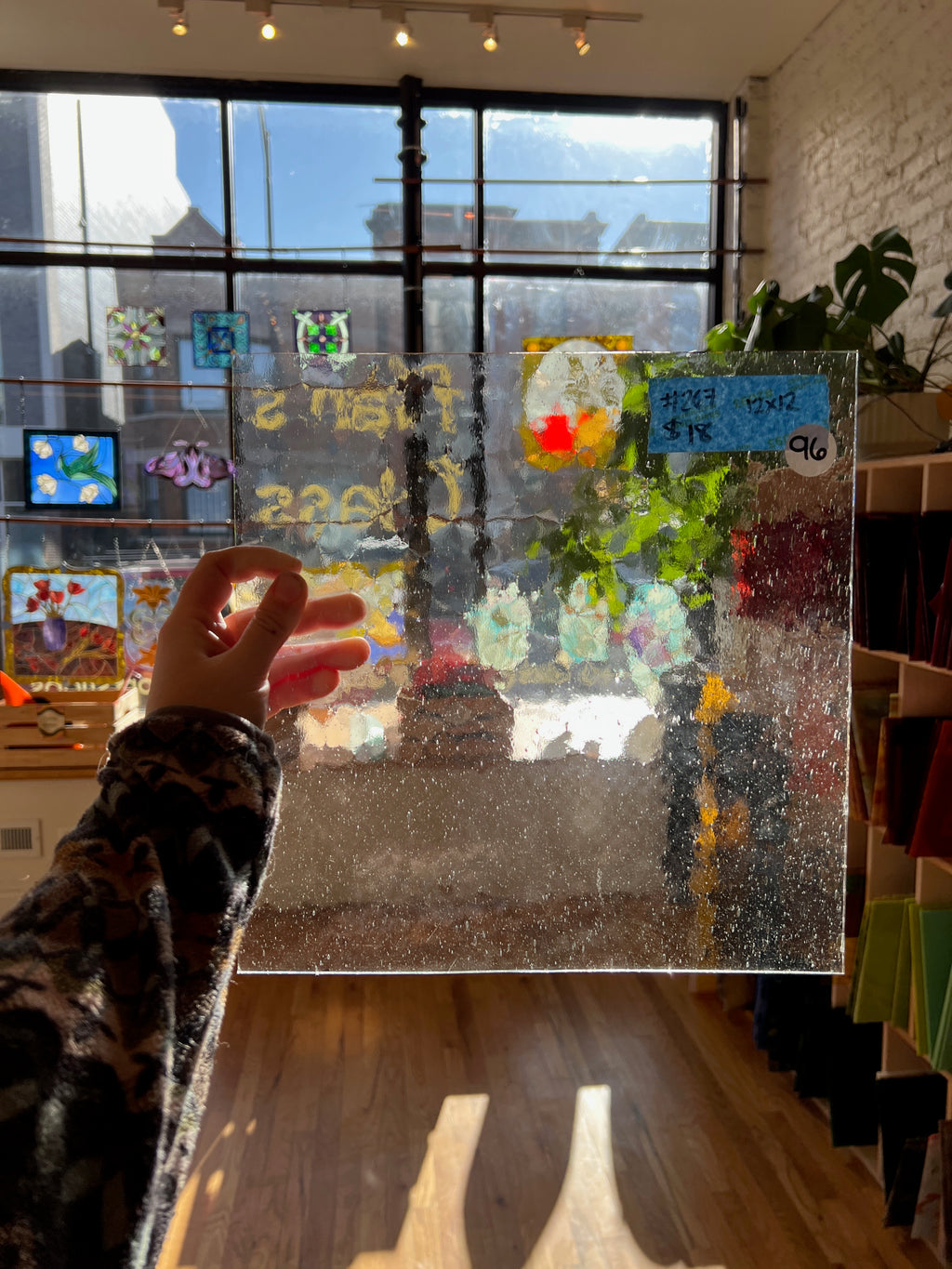 Glass panel with colorful drawings and text in a room with large windows.