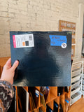 Person holding a blue glass sheet with price tags in a store setting