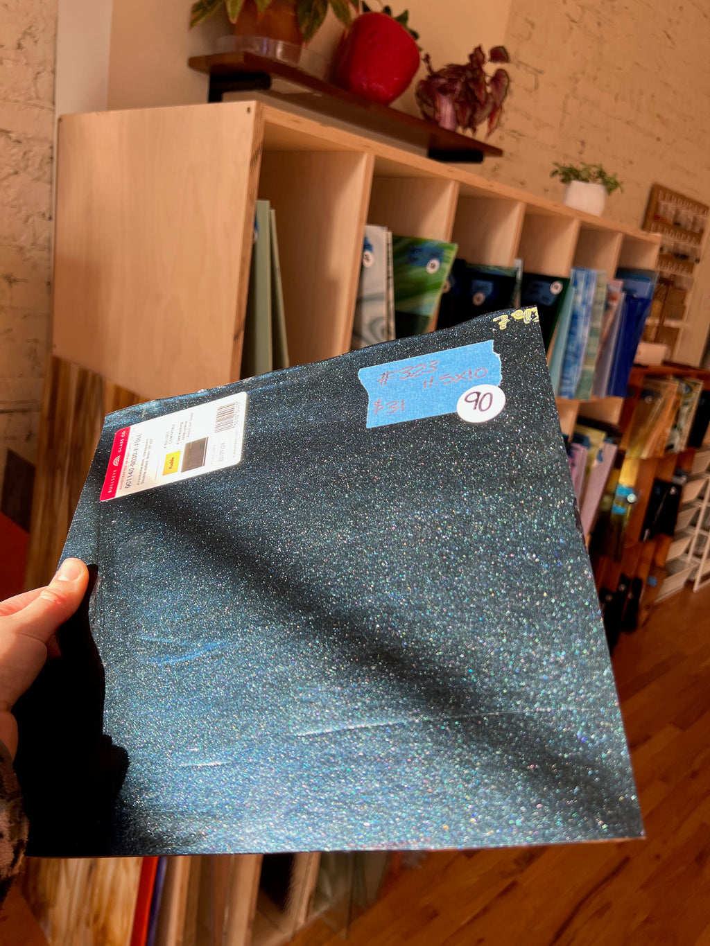 Person holding a blue glass sheet with a blurred indoor background